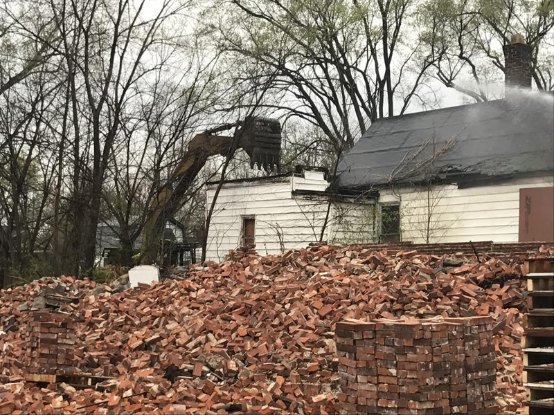 A pile of bricks from a demolished building partially obstruct the view of crews starting the demolition of a second property on Greer Avenue in St. Louis.